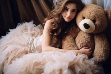 Young adult caucasian woman in wedding dress holding a teddy bear in her arms , wedding picture or female transition from childhood to adulthood