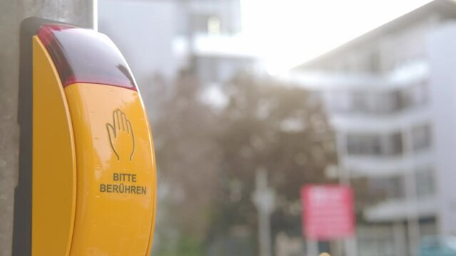 male hand presses yellow button to turn on traffic light pedestrian crossing, in German PRESS, participation in traffic management through activation of buttons, collaborative approach urban mobility