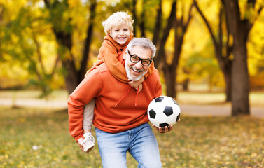 Portrait of happy grandfather and grandson with ball while playing football   in park. - 643641936