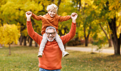 Happy   family grandfather and grandson have fun on  walk in autumn park.