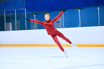 Concentration and motivation. Teen girl in red sportswear, figure skating athlete in motion on ice rink arena, training. Concept of professional sport, competition, sport school, health, hobby, ad