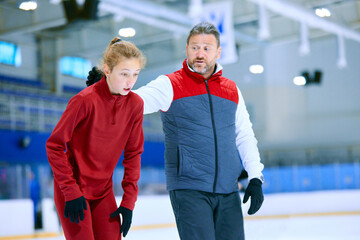 Coaching and assistance. Man, professional coach teaching girl to skate. Figure skating athletes on ice rink arena. Concept of professional sport, competition, sport school, health, hobby, ad © master1305