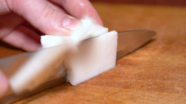 Slicing of salted pork fatback on cutting board, close-up. Ukrainian traditional food - salo