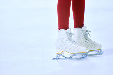 Close-up cropped image of female legs in red leggings and white skates on ice skate arena. Training and skating. Concept of professional sport, competition, sport school, health, hobby, ad