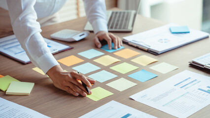 Businesswoman writing data in sticky notes on table to sharing ideas about strategy of new business