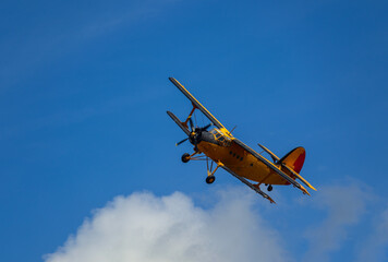 Antonov AN-2 biplane fly on cloudy sky. Old yellow historic plane from side