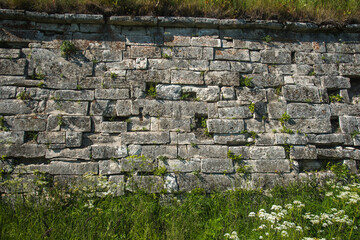 the old ancient stone wall of the fortress is overgrown with grass in places