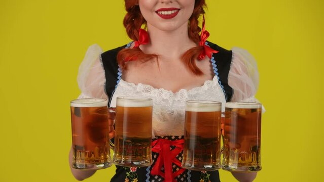 Close up yellow background isolated video of an unrecognizable young German woman, waitress wearing a traditional costume, offering four glasses of beer.