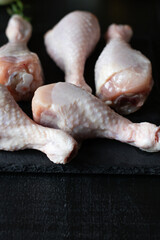 Raw chicken legs on slate plate. on wooden background. closeup