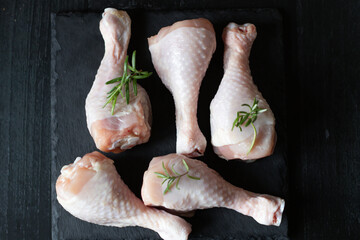 Raw chicken legs on slate plate. on wooden background. closeup