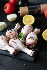 Raw chicken legs on slate plate. on wooden background. closeup
