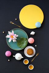 Flat lay Mid-autumn festival food and drinks - mooncake and tea set on black background.