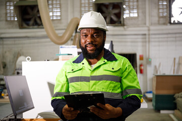 Portrait. African male engineer using a tablet computer. The background is a CNC cutting machine in the factory.