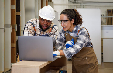 Team of professional carpenters men and women laptop computers in education and design Crafting furniture in the factory