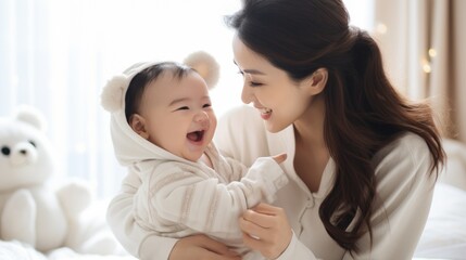 New Asian mom playing with cute newborn baby on bed smiling and happy and baby