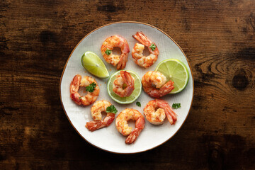 Shrimps, overhead flat lay shot. Fried shrimp with lime on a white plate, shot from the top on a rustic wooden background. Gourmet dish