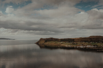 A small village reflecting in the ocean with a vast landscape of mountains in the background