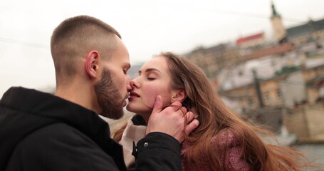 Kisses and hugs of a young couple in love. A romantic meeting of a young couple in the city center on a gloomy autumn day. Happy boy and girl hug, kiss, enjoying time together.