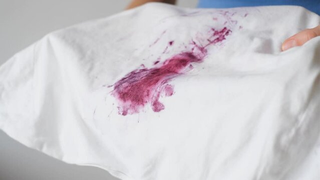 The hands showing stain of fruit or berries on a white cloth. Spoiled clothes. Dirty stain for cleaning concept.
