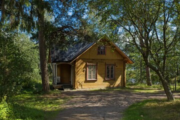 Fototapeta na wymiar Small wooden yellow hut inside a forest park in summer on the island of Seurasaari, Helsinki, Finland.