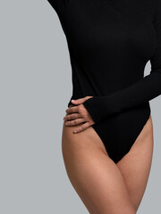Fototapeta premium Female body in black bodysuit. Smooth skin in bikini area