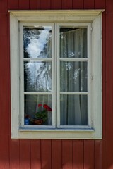 Old weathered white framed window on traditionally red painted wood building.