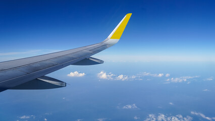 Naklejka na ściany i meble Airplane wing on a background of blue sky flight time