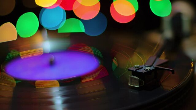 Turntable against the background of multi-colored spots in the dark, close-up
