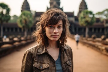 Naklejka premium Environmental portrait photography of a satisfied girl in her 40s wearing a classic leather jacket at the angkor wat in siem reap cambodia. With generative AI technology