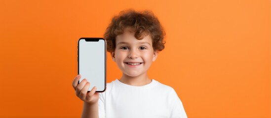 Kid s educational mobile app Little boy with smartphone smiling for school over orange background - obrazy, fototapety, plakaty