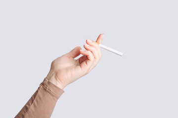 Woman's hand holding a cigarette. The concept of the dangers of smoking