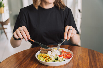 Girl has breakfast vegetable salad with cheese and eggs and rye bread on a white plate.