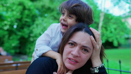 Careless small boy choking mom while playing. Kid not knowing play limits, upset mother, real life