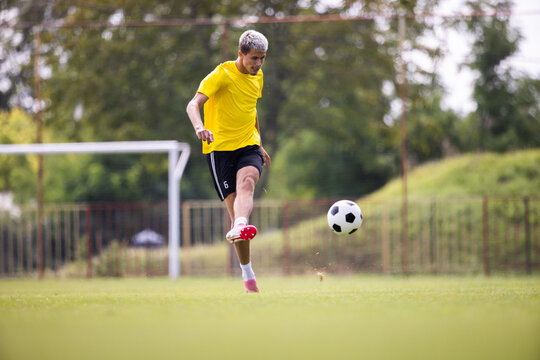 Soccer player kicks ball in a field