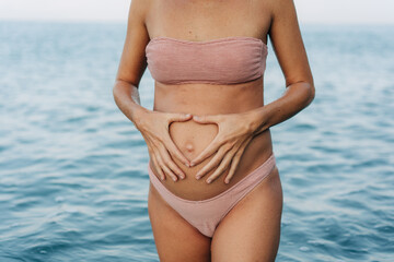 Large pregnant female belly of an anonymous woman on the background of the sea.