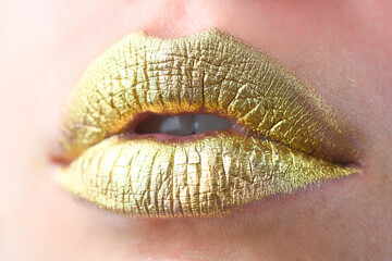 Fototapeta premium Close up female plump lips with gold. Golden glitter lipstick. Shine style for sexy lip. Sensual woman lips. Luxury golden mouth. Glamour gold lips. Golden lips with golden paint or metallic lipstick.