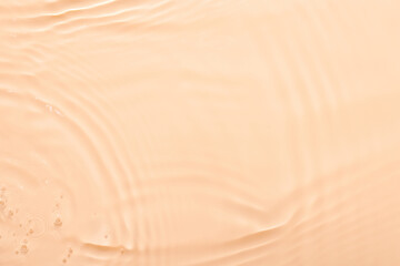 Water beige surface abstract background. Waves and ripples texture of cosmetic aqua moisturizer with bubbles.