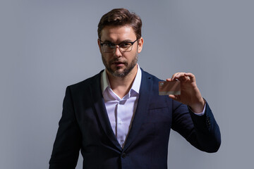 Portrait of businessman showing plastic credit card against grey background. Business and success concept. Online shopping. On-line payment. Balance on credit card.