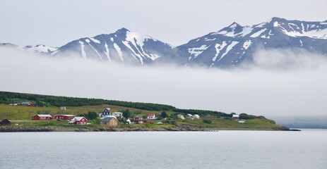 Hrisey Island under the snowy mountains and fog in Eyjafjordur, Iceland