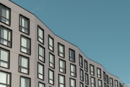 Side view of a building with many windows and metal facade in a minimalistic style against a blue sky