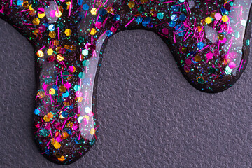 Colorful glitter sparkle confetti background liquid drops of paint color flow down on black canvas. Dark multicolored glitter paint dripping on the black wall