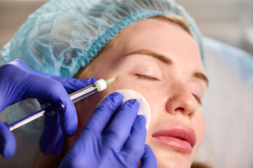 Cosmetologist injects substance in patient modifying face to make non-surgical correction. Filler...