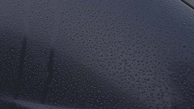 Water drops on dark blue automobile surface after rain. Wet car background.