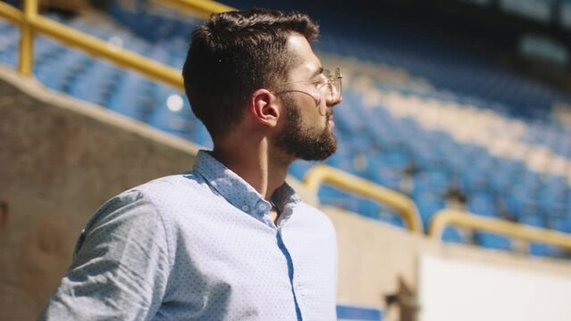 Businessman in formal wear standing on sport stadium, spreading hands in success. Money win. Good luck. Concept of sport, fan, betting and finances, gambling, bookmaker