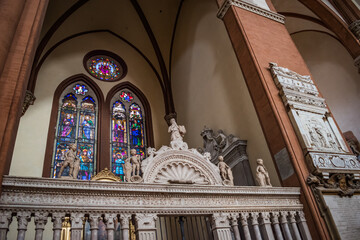 Gate decorated with statues and colorful stained glass windows with religious scenes inside the Basilica di San Petronio, Bologna ITALY © Liliana