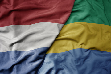 big waving national colorful flag of netherlands and national flag of gabon .