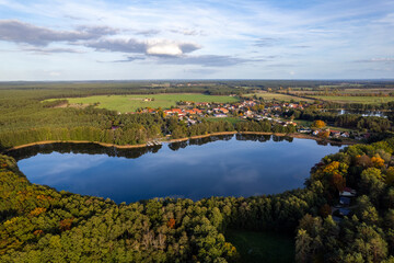 Fototapeta na wymiar Aerial shot of beautiful lake surrounded by forest in a calm autumn day. Germany. 4K video.