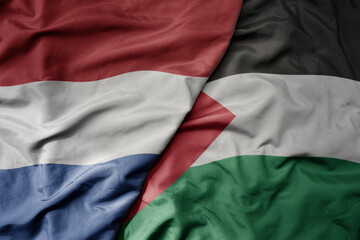 big waving national colorful flag of netherlands and national flag of palestine .
