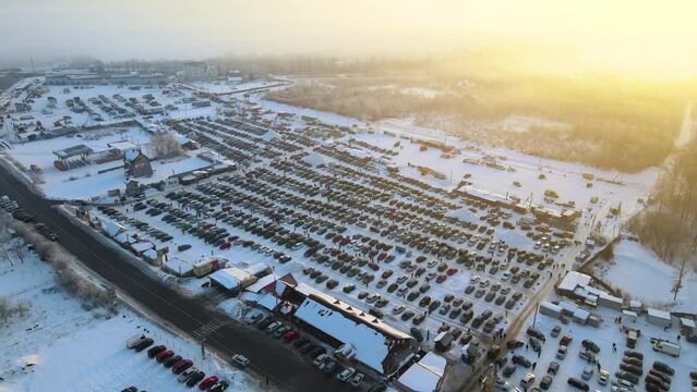 Aerial view of vehicle open market lot with many cars for sale parked and people customers walking in winter