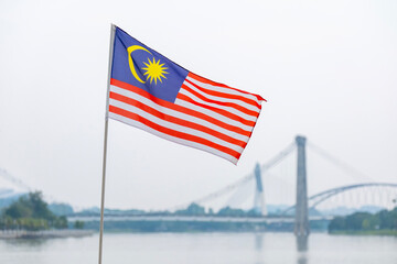 The Malaysia flag is also known as Jalur Gemilang waving with a city in the background. Independence Day or Merdeka Day celebration on 31 August and Hari Malaysia on 16 September, copy space concept.